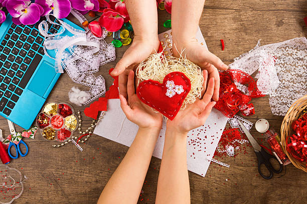Materials and tools for hand decoration for Valentine's Day on a sacking. Female hands give red heart in male hands.. Love and valentine concept.